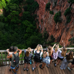 Turistas observan guacamayas bandera volando sobre el Buraco das Araras en Mato Grosso do Sul, Brasil