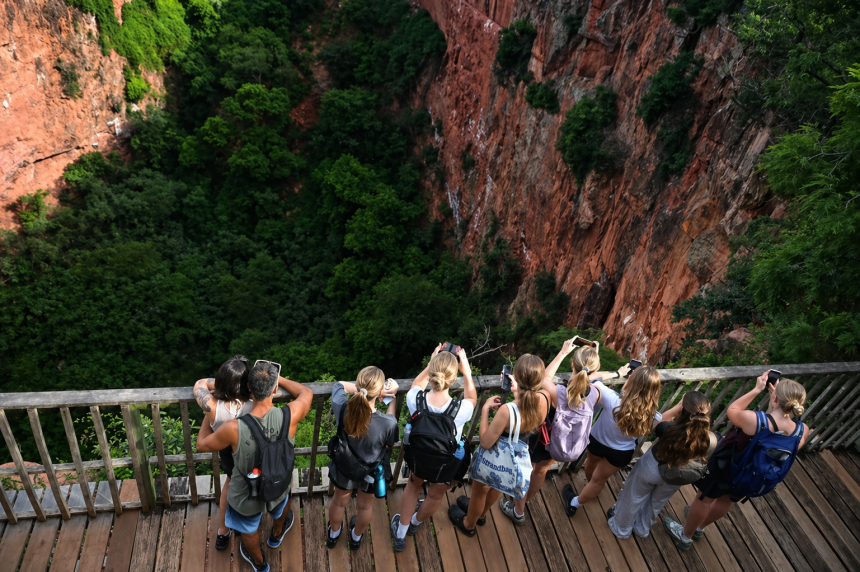 Turistas observan guacamayas bandera volando sobre el Buraco das Araras en Mato Grosso do Sul, Brasil